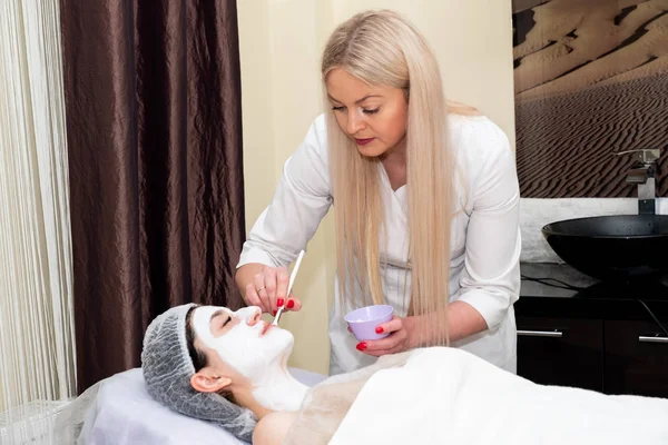Yüz soyma maskesi, kaplıca güzellik tedavisi, cilt bakımı. Güzellik salonunda güzellik uzmanı bir kadının yüz bakımını alıyor..