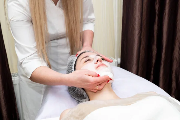 Face peeling mask, spa beauty treatment, skincare. Woman getting facial care by beautician at spa salon.