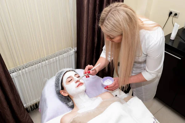 Face peeling mask, spa beauty treatment, skincare. Woman getting facial care by beautician at spa salon.