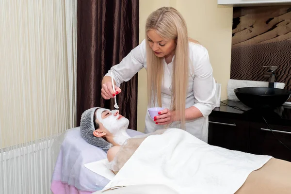 Yüz soyma maskesi, kaplıca güzellik tedavisi, cilt bakımı. Güzellik salonunda güzellik uzmanı bir kadının yüz bakımını alıyor..