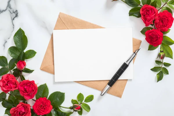 Tarjeta postal burlona con sobre de papel artesanal, marco de flores de pluma y rosa sobre fondo de piedra de mármol. Composición de estilo mínimo, posición plana. Vista superior. Concepto de carta de amor . — Foto de Stock