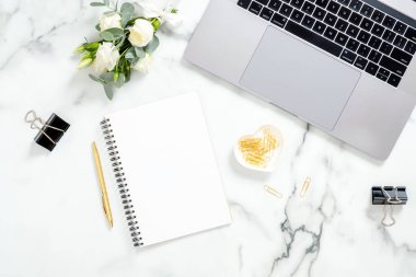 Dizüstü bilgisayar, günlük, altın kırtasiye, beyaz mermer yüzey üzerinde çiçek buketi ile Mermer ofis masası masa. Düz yatıyordu, üst görünüm kadınsı arka plan. Moda blogger çalışma alanı.