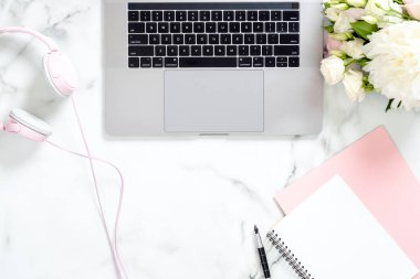 Dizüstü bilgisayar, kağıt not defteri, kalem, gül çiçek buketi ile modern mermer ofis masası masa, kopya alanı ile kulaklık Minimal düz yatıyordu tarzı kompozisyon, üst görünüm. Kadınsı çalışma alanı.