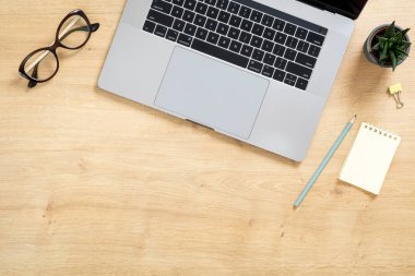Dizüstü bilgisayar, kağıt not defteri, lezzetli bitki, gözlük ile modern ahşap ofis masası masa. Kopya alanı ile üst görünüm, düz yatıyordu. Kadınsı çalışma alanı kavramı.