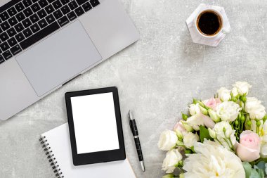 Düz yatıyordu ev ofis masası. Kadın çalışma alanı dizüstü bilgisayar, boş kopya alanı mockup ekran tablet, kahve fincanı, günlük, beton taş arka plan üzerinde çiçekler. Üst görünüm kadınsı arka plan