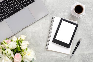 Dizüstü bilgisayar, boş kopya alanı maket ekran tablet, çiçekler, kahve fincan ve beton taş arka plan üzerinde malzemeleri ile Ofis masası masa. Kopya alanı ile üst görünüm, düz yatıyordu. Kadınsı çalışma alanı