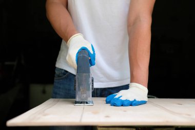 Atölyede elektrikli jig testere kullanarak eldiven ahşap işçisi. Yan görünüm. Marangozluk konsepti.