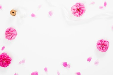 Pembe çiçekler açan merkezinde boş alan ile minimal düz yatıyordu tarzı kompozisyon. Beyaz arka plan üzerinde pembe gül ve kurdele ile üst görünüm çiçek dekoratif çerçeve.