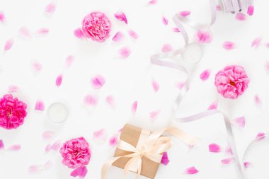 Pembe gül çiçeği tomurcukları, yaprakları, kurdele, beyaz arka plan üzerinde hediye kutusu ile Yaratıcı düğün kompozisyon. Minimal düz döşeme tarzı kompozisyon, üst görünüm. Kadın masası, moda blogger, güzellik konsepti.