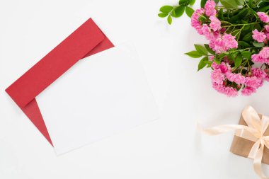 Düz yatıyordu ev ofis masası. Boş kağıt kart, kırmızı kağıt zarf, pembe gül çiçekleri, hediye kutusu ile kadın çalışma alanı. Üst görünüm kadınsı arka plan. Aşk mektubu kavramını yazma.