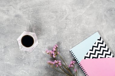 Kahve fincanı, pembe çiçekler, beton yüzey üzerinde kağıt defter ile düz yatıyordu kompozisyon. Üst görünüm kadın ev ofis masası. Rahat sabah kahvaltı konsepti.