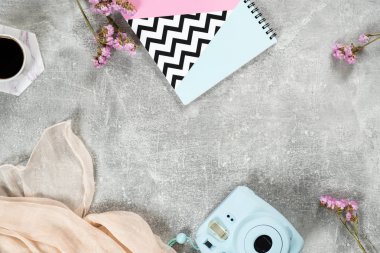 Beton yüzey güzellik blogger öğeleri Üst görünüm şık çerçeve seti. Kadınsı erişilebilirlik ile Düz yatıyordu ev ofis masası: anlık film kamera, kağıt defter, eşarp, kahve fincanı, çiçek.