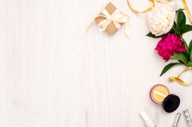 Üst görünüm çerçeve kadın öğeleri yapılmış: kozmetik, şakayık çiçekler, ruj, ahşap arka plan üzerinde hediye kutusu. Kadınaksesuarları, ev ofis masası konsepti ile minimal düz yatıyordu stil kompozisyon. Kopya aralığı