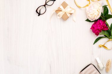 Üst görünüm çerçeve kadın öğeleri yapılmış: kozmetik, pion çiçekler, çanta, ahşap arka plan üzerinde hediye kutusu. Kadınaksesuarları, ev ofis masası konsepti ile minimal düz yatıyordu stil kompozisyon. Kopyalama alanı