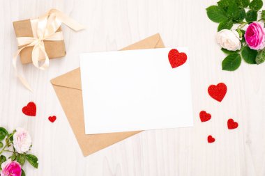 Kırmızı kalp şekilleri ve metin için alan, kurdele yay ve ahşap bir arka plan üzerinde gül çiçekleri ile hediye kutusu ile üst görünüm tebrik kartı. Minimal düz yatıyordu tarzı afiş mockup, Sevgililer Günü kavramı