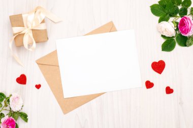 Kırmızı kalp şekilleri ve metin için alan, kurdele yay ve ahşap bir arka plan üzerinde gül çiçekleri ile hediye kutusu ile üst görünüm tebrik kartı. Minimal düz yatıyordu tarzı afiş mockup, Sevgililer Günü kavramı