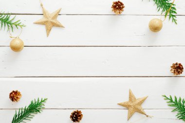 Noel kompozisyonu. Köknar ağacı dallarından yapılmış çerçeve, altın dekor yıldızları, ahşap beyaz arka plan üzerine koniler... Noel, kış tatili, yeni yıl konsepti. Kartpostal şablonu mockup.