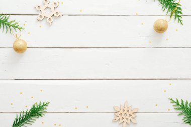 Minimal Noel kompozisyonu. Altın topları ile Düz yatıyordu köknar ağacı dalları, beyaz ahşap masa üzerinde el yapımı kar taneleri. Düz döşeme, üst görünüm, kopyalama alanı. Noel çerçevesi arka plan, afiş mockup.