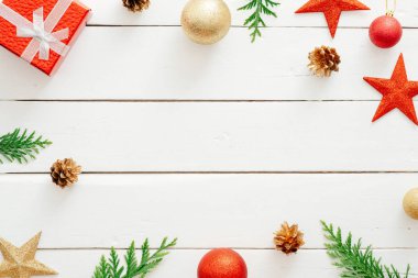 Noel kompozisyonu. Kırmızı hediyeler, süslemeler, köknar ağacı dalları, ahşap beyaz arka plan üzerinde çam kozu. Noel, kış tatili, yeni yıl konsepti. Düz döşeme, üst görünüm, kopyalama alanı