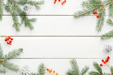 Noel kompozisyonu. Ahşap beyaz arka plan üzerinde köknar ağacı dalları ve kırmızı berry yapılmış Noel çerçevesi. Düz döşeme, üst görünüm, kopyalama alanı. Noel arka plan, Xmas kartpostal şablonu, afiş mockup