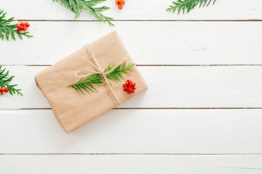 Noel kompozisyonu. Noel hediyesi, köknar ağacı dalları ve beyaz ahşap arka plan üzerinde kırmızı süslemeler. Düz döşeme, üst görünüm, kopyalama alanı.