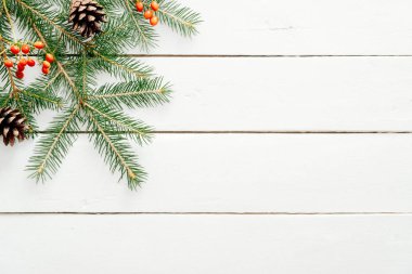 Noel çerçeve köknar ağacı dalları, kırmızı çilek, rustik ahşap beyaz masa üzerinde çam kozalağı yapılmış. Noel, Yeni Yıl, kış tatilleri kavramı. Düz döşeme, üst görünüm, kopyalama alanı