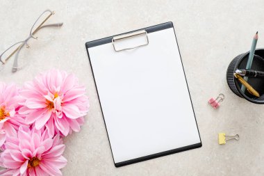Düz yatıyordu ev ofis masası. Kağıt pano mockup, pembe dahlia çiçekler, taş arka plan kadın aksesuarları ile Kadın çalışma alanı. Üst görünüm kadınsı arka plan. Moda blog kahraman.