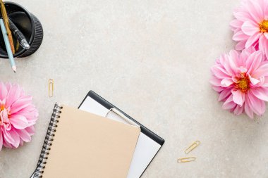 Düz yatıyordu ev ofis masası. Kağıt pano, pembe dahlia çiçekler, taş arka plan kadın aksesuarları ile Kadın çalışma alanı. Üst görünüm kadınsı arka plan. Moda blog kahraman.