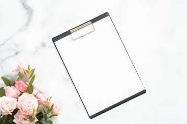 Beyaz mermer taş arka plan üzerinde boş kağıt pano mockup ve pembe gül çiçek buketi ile Modern ev ofis masası çalışma alanı. Flatlay, üst görünüm.