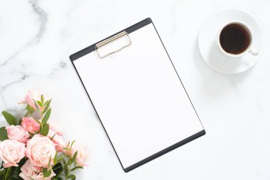Boş kağıt pano mockup, pembe gül çiçek buketi, beyaz mermer taş arka plan üzerinde kahve fincanı ile Modern ev ofis masası çalışma alanı. Flatlay, üst görünüm.