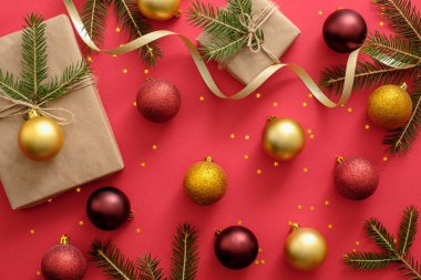 Noel veya Yeni Yıl kompozisyon. Noel sarılmış kurdele ve köknar ağacı dalları, kırmızı arka plan üzerinde Xmas topları sunar. Düz yatıyordu, üstten bak, tepede. Noel, kış, yeni yıl konsepti.