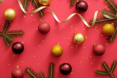 Noel süslemeleri, topları, altın kurdele, köknar ağacı dalları, kırmızı arka plan konfeti ile Noel kompozisyon. Noel, kış, yeni yıl konsepti. Düz döşeme, üst görünüm, genel merkez
