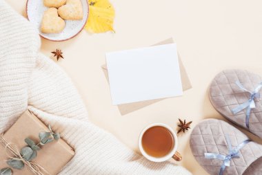 Sonbahar flatlay kompozisyon. Beyaz örme ekose, mektup, hediye kutusu, terlik, çay bardağı, pastel bej arka plan üzerinde düşmüş yaprakları ile Kadınsı masaüstü. Düz yatıyordu, üstten bak. Sonbahar, sonbahar konsepti.