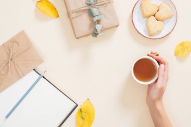 Düşmüş yaprakları, kitap, kurabiye, hediye kutusu ile sonbahar arka plan üzerinde çay kadın el tutan. Sonbahar kompozisyon, düz yatıyordu, üst görünüm, tepedeki Cozy ev masaüstü, hygge kavramı.
