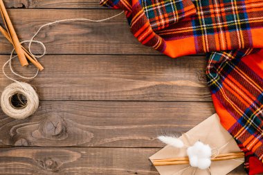 Flatlay sonbahar kompozisyon. Çerçeve kırmızı ekose, tarçın çubukları, ip, ahşap arka plan üzerinde zarf. Düz döşeme, üst görünüm, kopyalama alanı. Rahat ev masası, hygge, sonbahar sonbahar konsepti