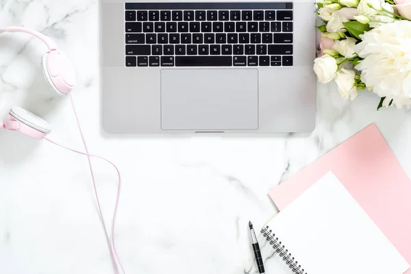 Dizüstü bilgisayar, kağıt not defteri, kalem, gül çiçek buketi ile modern mermer ofis masası masa, kopya alanı ile kulaklık Minimal düz yatıyordu tarzı kompozisyon, üst görünüm. Kadınsı çalışma alanı.