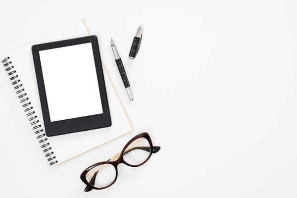 Flat Lay papper anteckningsbok, e-bok läsare glasögon på vit bakgrund. Översta vyn feminina dagbok, brevpapper och elektronisk enhet på Home Office Desk. — Stockfoto