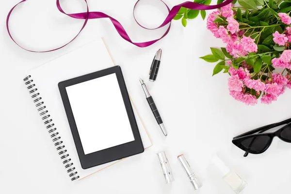 空白の画面タブレットの電子ブック、女性のアクセサリー、メガネ、紙のノート、白い背景にピンクのバラの花の花束を持つモダンなホームオフィスデスクワークスペース。フラットレイメステーブル、トップビュー. — ストック写真
