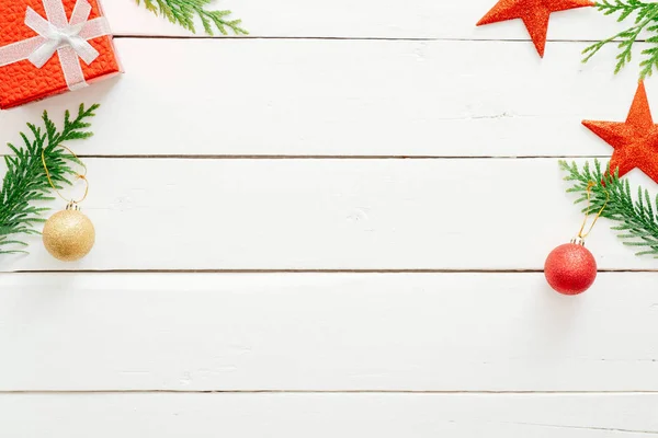 クリスマスの作曲。モミの木の枝、赤いギフトボックス、素朴な木製の白い背景にクリスマスの装飾。最小平らな横、上の眺め、コピースペース。Xmas、新年のグリーティングカードモックアップ — ストック写真