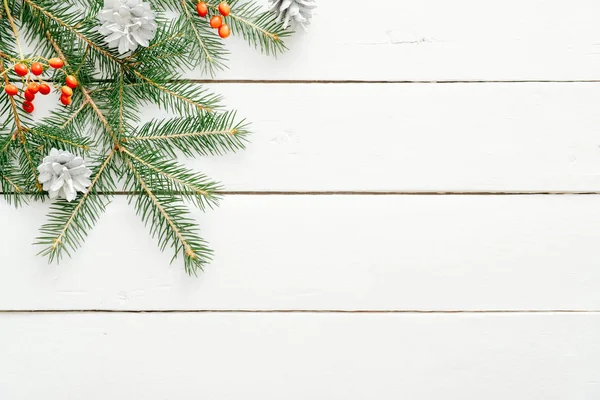 Noel kompozisyonu. Ahşap beyaz arka plan üzerinde köknar ağacı dalı ve kırmızı dut yapılmış Noel çerçevesi. Düz döşeme, üst görünüm, kopyalama alanı. Noel arka plan, Xmas kartpostal şablonu, afiş mockup