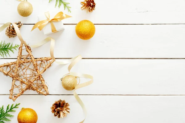 Beyaz ahşap arka plan üzerinde altın Noel süslemeleri ve köknar dalları ile Flatlay kompozisyon. Düz döşeme, üst görünüm, kopyalama alanı. Noel, Yeni Yıl, kış konsepti. Banner mockup, kartpostal şablonu
