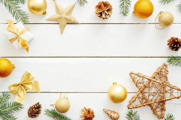 Noel kompozisyonu. Flatlay altın süslemeler, topları, yıldız, beyaz ahşap arka plan üzerinde köknar ağacı dalı. Düz döşeme, üst görünüm, kopyalama alanı. Yeni yıl, Noel, kış konsepti. Xmas afiş mockup.