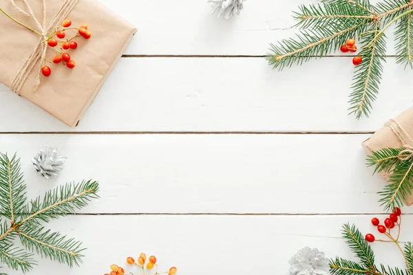 Noel kompozisyonu. Hediyeler, köknar ağacı dalları, ahşap beyaz masa üzerinde kırmızı süslemeler. Noel arka plan, Kış tatili, Yeni Yıl kavramı. Düz döşeme, üst görünüm, kopyalama alanı