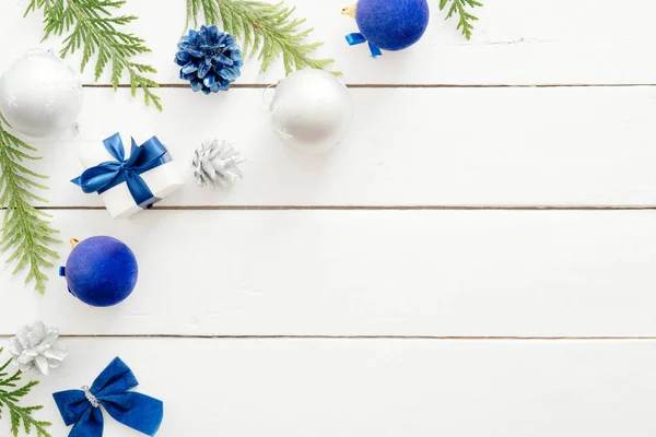 青いボール、モミの木の枝、ギフトボックス、木製の白い背景に装飾品とクリスマスカード。新年の休日のお祝いのバナーモックアップ。クリスマスカードテンプレート。フラットレイ、トップビュー、オーバーヘッド — ストック写真