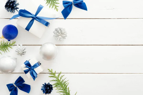 青いボール、ギフトボックス、木製の白い背景に装飾品とクリスマスカードテンプレート。新年の休日のお祝いのバナーモックアップ。クリスマスカードフラットレイ、トップビュー、オーバーヘッド. — ストック写真