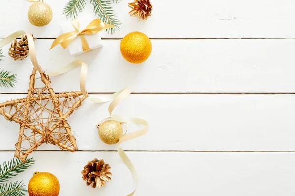 黄金の装飾、ボール、星、贈り物、リボン、モミの木の枝、木製の白い背景に松ぼっくりを持つクリスマスの休日の構成。フラットレイ、トップビュー、コピースペース。クリスマスの背景. — ストック写真