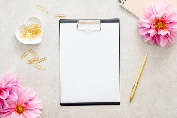 Düz yatıyordu ev ofis masası. Kağıt pano mockup, pembe dahlia çiçekler, taş arka plan kadın aksesuarları ile Kadın çalışma alanı. Üst görünüm kadınsı arka plan. Moda blog kahraman.