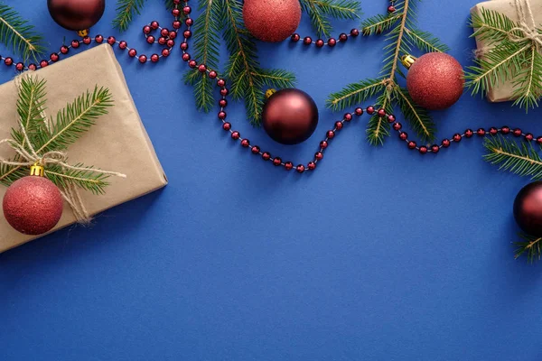 Marco hecho de decoraciones de Navidad, ramas de árbol de Navidad, bolas, regalos sobre fondo azul. Plantilla de postal o maqueta. Acostado plano, vista superior, arriba. Navidad en el concepto de año nuevo . — Foto de Stock