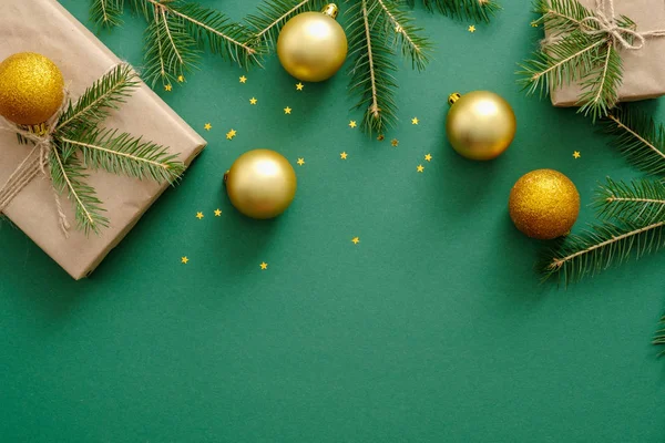Різдвяна композиція. Плоскі ялинкові кульки, золоті прикраси, подарункові коробки, загорнуті в крафт-папір, ялинкові гілки на зеленому тлі. Різдвяний або новорічний шаблон макета банерів з копіювальним простором . — стокове фото