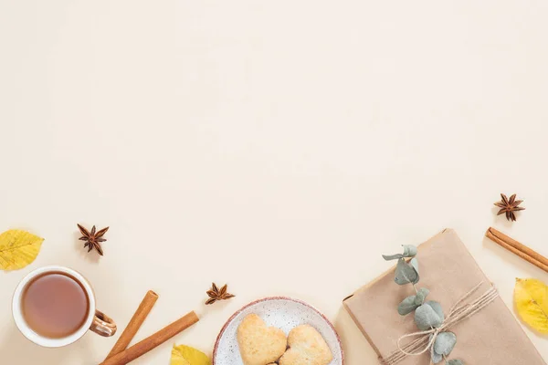 平底秋季组成。框架由一杯茶，秋季干叶，肉桂棒，饼干，礼品盒在柔和的米色背景。平铺，顶视图，复制空间。秋季最小概念. — 图库照片